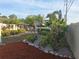 Landscaped backyard featuring palm trees, lush foliage, rock ground cover, and a screened patio with outdoor furniture at 3357 Hunt Club Dr, Clearwater, FL 33761