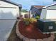 Well-kept side yard featuring a mulch bed with mature plants, utility access, and fence-lined property at 3357 Hunt Club Dr, Clearwater, FL 33761