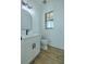 Modern half bathroom with white vanity, black faucet, black trim window, and wood-look flooring at 3515 Powerline Rd, Lithia, FL 33547