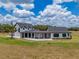 An exterior view of this modern farmhouse with its connecting covered patio, white siding, and black trim set against a green lawn at 3515 Powerline Rd, Lithia, FL 33547