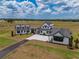 An aerial view showcases a modern farmhouse with connecting units, white siding, black trim, a paved driveway, and landscaped grounds at 3515 Powerline Rd, Lithia, FL 33547