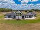 Striking view of this modern farmhouse showcases its white siding, black trim, connecting covered patio, and a lush green lawn at 3515 Powerline Rd, Lithia, FL 33547
