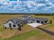 A contemporary farmhouse featuring white siding, black trim, manicured grounds, and an adjacent building with solar panels at 3515 Powerline Rd, Lithia, FL 33547