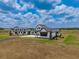 A modern farmhouse with white siding and black trim, showcases a connecting covered walkway and well-manicured grounds at 3515 Powerline Rd, Lithia, FL 33547