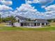 A picturesque modern farmhouse featuring a white exterior, black trim, connecting covered patio and a lovely green lawn at 3515 Powerline Rd, Lithia, FL 33547