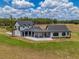 A modern farmhouse with black trim and white siding features a connecting covered patio and a beautiful green lawn at 3515 Powerline Rd, Lithia, FL 33547