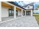 White home exterior showcases an expansive patio with dark window frames, wooden ceiling and manicured lawn at 3515 Powerline Rd, Lithia, FL 33547