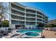 Exterior view of building with a swimming pool, hot tub and lounge area at 3805 Gulf Blvd # 504, St Pete Beach, FL 33706