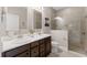 Well-lit bathroom featuring a double sink vanity with a large mirror and glass enclosed shower at 3877 Burdick Loop, Odessa, FL 33556