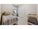 Comfortable bedroom with a crib, neutral paint, tile flooring, and bright window to enhance the home's appeal at 3877 Burdick Loop, Odessa, FL 33556