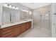 Bright bathroom featuring a double vanity, a large mirror, and a glass enclosed shower at 4063 Medicci Ln, Wesley Chapel, FL 33543