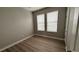 Bright bedroom featuring wood floors, neutral paint, and natural light from the two windows at 4063 Medicci Ln, Wesley Chapel, FL 33543