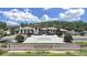 Community clubhouse with lush landscaping, palm trees, and a large parking area at 4063 Medicci Ln, Wesley Chapel, FL 33543