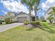 Charming single-story home featuring a well-manicured lawn and tropical landscaping with palm trees at 4063 Medicci Ln, Wesley Chapel, FL 33543