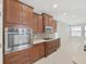 A modern kitchen showcases stainless steel appliances, brown wood cabinetry and tile backsplash at 4063 Medicci Ln, Wesley Chapel, FL 33543