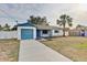 Charming home with a blue garage door, blue accents, and a well-maintained lawn at 416 Flamingo Dr, Apollo Beach, FL 33572
