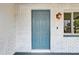 Close-up of a stylish blue front door framed by white brick, complemented by an outdoor light at 416 Flamingo Dr, Apollo Beach, FL 33572