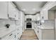 Bright kitchen with white cabinets, herringbone backsplash, stainless steel appliances, and wood-look flooring at 416 Flamingo Dr, Apollo Beach, FL 33572
