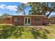 Rear exterior of a brick home featuring a deck, french doors and a grassy backyard at 4512 24Th Ave S, Tampa, FL 33619