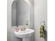 Stylish half-bathroom features pedestal sink, arched mirror, and modern fixtures at 4717 W Lawn Ave, Tampa, FL 33611