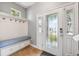 Inviting entryway with custom bench seating, coat hooks, storage, and a beautiful decorative glass front door at 4717 W Lawn Ave, Tampa, FL 33611