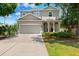 Charming two-story home featuring a two-car garage, landscaped yard, and covered entryway with arched columns at 4717 W Lawn Ave, Tampa, FL 33611