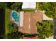 Aerial view of a home with a private screened-in pool, surrounded by lush landscaping and a tile roof at 5242 Venice Ne Way, St Petersburg, FL 33703