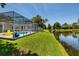 Backyard with screened pool, lush landscaping, and waterfront pond at 5242 Venice Ne Way, St Petersburg, FL 33703