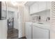 Well-lit laundry area with white washer, dryer, and cabinets, ensuring a clean and efficient space for laundry tasks at 5666 Gardens Dr # 202, Sarasota, FL 34243