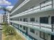 Three-story condo exterior showcasing white balconies and palm trees, offering a bright and airy feel at 5970 80Th N St # 204, St Petersburg, FL 33709