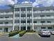 A three-story condo building with white pillars, blue trim, and parking spaces in front at 5970 80Th N St # 204, St Petersburg, FL 33709
