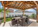 Enchanting outdoor dining area nestled under a wooden pergola with lush landscaping for relaxed entertainment at 6398 Bar S Bar Trl, Zephyrhills, FL 33541