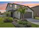 Charming two-story home with a well-manicured lawn and tropical landscaping with the sunset in the background at 6398 Bar S Bar Trl, Zephyrhills, FL 33541
