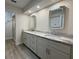 Bathroom featuring double vanity with gray cabinets, granite countertop and modern, lighted mirrors above each sink at 6533 Brentwood Dr, Zephyrhills, FL 33542