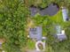 Aerial view of home, pond with fountain, pool, lush green trees, and circular driveway at 6703 Towhe Dr, Seffner, FL 33584
