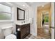 Bathroom with a dark vanity, window, and an open doorway leading to a bedroom at 6703 Towhe Dr, Seffner, FL 33584