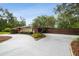 Ranch style home with red siding, stone accents, mature trees, and a circular driveway at 6703 Towhe Dr, Seffner, FL 33584
