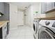 Well lit laundry room with gray cabinetry, butcher block counters, and stainless steel appliances at 6703 Towhe Dr, Seffner, FL 33584
