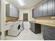 Bright laundry room with overhead cabinets, butcher block counter, and white front load appliances at 6703 Towhe Dr, Seffner, FL 33584