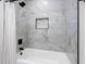 Bright bathroom featuring white tub and beautiful marble-style tile with modern black fixtures and inset at 8307 Boxwood Dr, Tampa, FL 33615