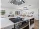 Kitchen island with cooktop and stainless steel oven overlooks dining area with modern light fixture at 8307 Boxwood Dr, Tampa, FL 33615