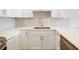Close-up of kitchen sink and quartz countertops with mosaic backsplash and modern stainless steel hardware at 100 Oakmont Ln # 305, Belleair, FL 33756