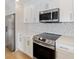 Updated kitchen featuring stainless steel appliances, white cabinets, mosaic backsplash, and a flat cooktop at 100 Oakmont Ln # 305, Belleair, FL 33756