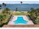 Beautiful pool area surrounded by palm trees and lounge chairs offers a relaxing oasis with water views at 100 Oakmont Ln # 305, Belleair, FL 33756