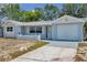 Charming single-story home with a well-maintained lawn and attached garage, painted in a cool, light blue at 10900 Queens Rd, Port Richey, FL 34668