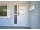 Close-up of a front door with decorative window and mailbox against blue brick exterior at 10900 Queens Rd, Port Richey, FL 34668