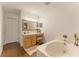 Bright bathroom featuring a soaking tub, wood-look floors, and vanity with lots of counter space at 10930 Banyan Wood Way, Riverview, FL 33579