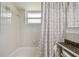 Bathroom with tub and shower, featuring a shower curtain and bright natural light at 1150 Grand Blvd, Holiday, FL 34690