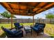 Backyard patio with outdoor seating under a wooden pergola with ceiling fan and views of the fenced yard at 1150 Grand Blvd, Holiday, FL 34690