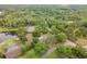 Aerial view showcases the home's location amidst lush greenery, nearby ponds, and beautiful mature trees at 1204 Ballinger Rd, Lutz, FL 33548